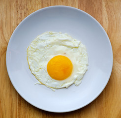 The fried egg is in a white round dish placed top view