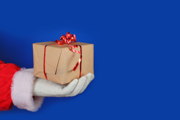 Santa Claus in white gloves holding gift box on blue background.