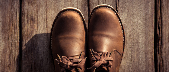 Brown stylish boots on wood background,  retro color