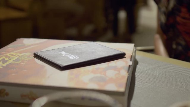 Paying a bill with cash in a restaurant. Woman leaves money in a small folder with the word "Bill" on it after eating pizza in a lounge bar.