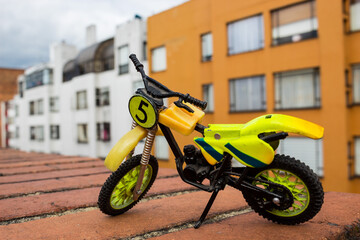 Fototapeta na wymiar Mini Motocross Bike Toy green and yellow with building Background