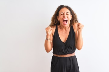 Obraz na płótnie Canvas Middle age woman wearing black casual dress standing over isolated white background celebrating mad and crazy for success with arms raised and closed eyes screaming excited. Winner concept