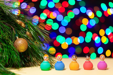 close-up wooden multi-colored little men lead a round dance and enjoy the holiday near the New Year tree against the background of many colorful lights. Picture for New Year's design, greeting card.