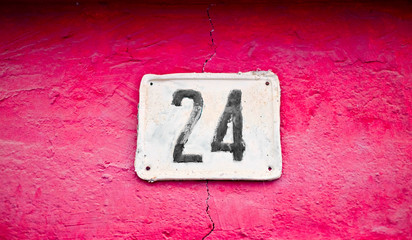 Number 24, twenty-four, black on a white plate, vivid red / pink background.