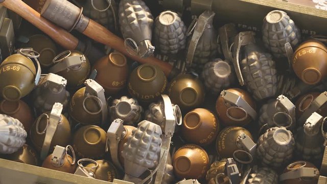 Close up of piled up different types of grenades in wooden ammunition box. 4k HD