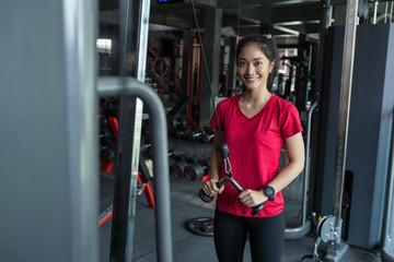 Beautiful muscular fit asian woman exercising building muscles in the gym, concept of healthy lifestyle