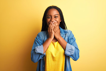 Young african american woman wearing denim shirt standing over isolated yellow background laughing...