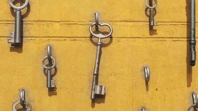 Animation of a key hanging on the hook with other keys around. Yellow wall. 4kHD