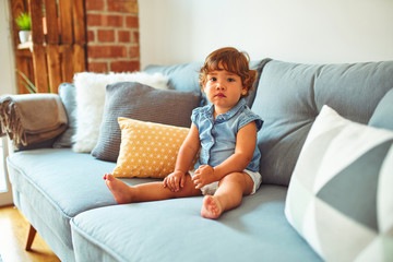 Beautiful toddler child girl wearing blue denim shirt sitting on the sofa