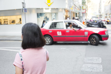 Young woman walking in Hongkong street with taxi cab in background. Traveler Asian girl in Hongkong city. Travel lifestyle concept.