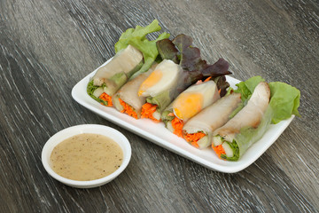 fresh vegetables spring rolls on white plate,  wood table background..