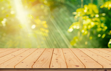 The wooden table top is blurred. The garden in the morning is used with the light of the sun for editing the product image or layout design.