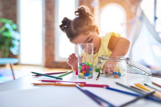 Beautiful toddler standing playing with chocolate colored balls on the table at kindergarten