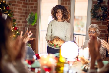 Beautiful group of women smiling happy and confident. Showing roasted turkey celebrating christmas at home