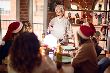 Beautiful group of women smiling happy and confident. On of them holding cup of wine speaking speech celebrating christmas at home