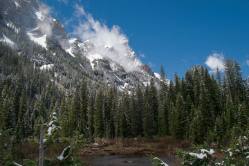 Fototapeta na wymiar Snow covered mountain peaks above the forest