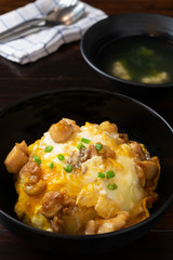 Oyakodon or donburi in black bowl with Miso soup on wooden table.