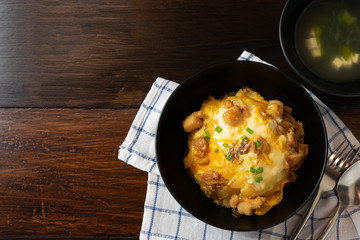 Oyakodon or donburi in black bowl with Miso soup on wooden table.