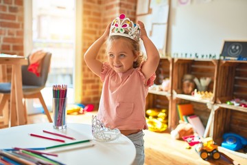 Beautiful blond toddler girl wearing princess crown standing at kindergarten © Krakenimages.com