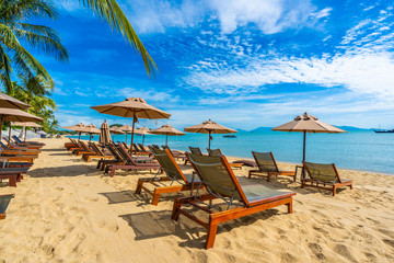 Beautiful tropical beach sea and ocean with coconut palm tree  and umbrella and chair on blue sky and white cloud