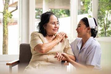 Beautiful nurse comforting female patient in the room.