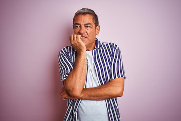 Handsome middle age man wearing striped shirt standing over isolated pink background looking...