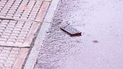 雨の日の道路に落ちたスマートフォン