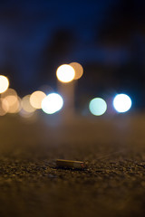 cigarette butt on the street at night with bokeh background street lights lit tip smoking 