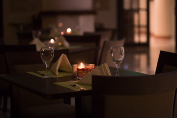 a table at a fancy restaurant candle light romantic dinner setting dim lighting 