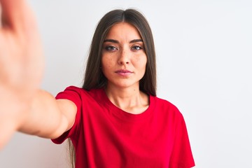 Beautiful woman wearing red t-shirt make selfie by camera over isolated white background with a...
