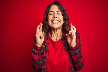 Young beautiful woman wearing casual jacket standing over red isolated background shaking and freezing for winter cold with sad and shock expression on face