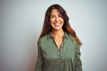 Young beautiful woman wearing green shirt standing over grey isolated background with a happy and...
