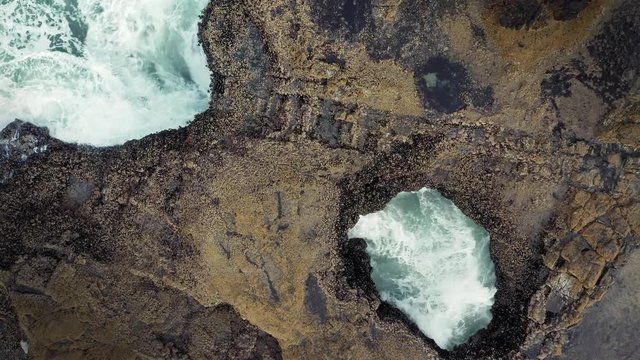 Aerial flying over rocky coastline and ocean waves at a hole in the rock called Thor's Well. Cape Perpetua, Oregon, USA