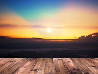 Fototapeta na wymiar Wood table top over sun at blurry sunrise sky background.