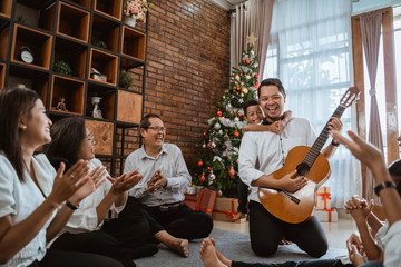 happy family playing guitar during christmas eve celebration at home