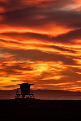 Dramatic sunset sky over the sea with silhouette of a lifeguard tower at the beach 