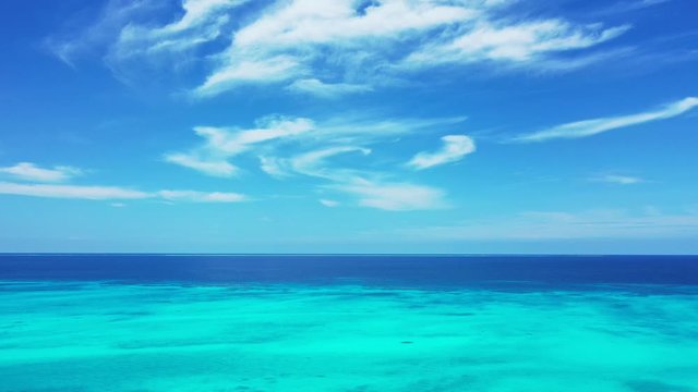 Paradise seascape with bright sky and frozen white clouds shining over deep blue ocean and turquoise lagoon in Bahamas, copy space
