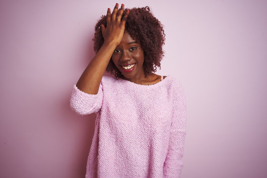 Young african afro woman wearing sweater standing over isolated pink background surprised with hand on head for mistake, remember error. Forgot, bad memory concept.