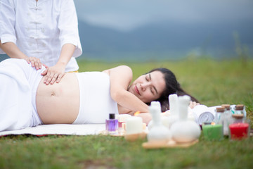 Pregnant women, spa massage, relax in a grass garden amidst beautiful nature