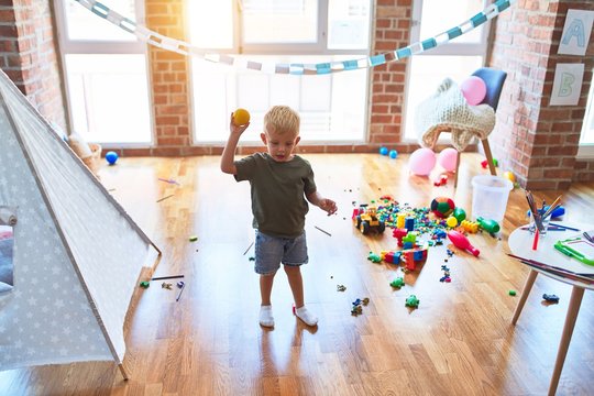 Young caucasian kid playing at kindergarten with toys. Preschooler boy happy at playroom.