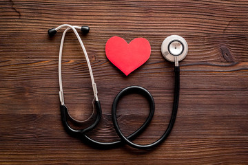 Health care concept. Heart icon and stethoscope on dark wooden background top view