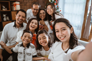 big family selfie on christmas day. asian people take picture using mobile phone