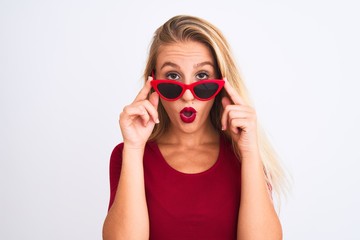 Young beautiful woman wearing red t-shirt and sunglasses over isolated white background afraid and shocked with surprise expression, fear and excited face.