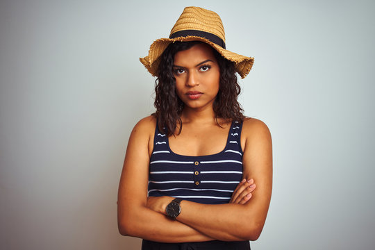 Beautiful transsexual transgender woman wearing summer hat over isolated white background skeptic and nervous, disapproving expression on face with crossed arms. Negative person.