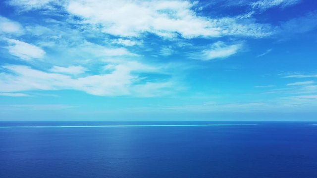 Paradise seascape with bright sky and veil of clouds reflecting on calm surface of navy blue ocean in Barbados, copy space