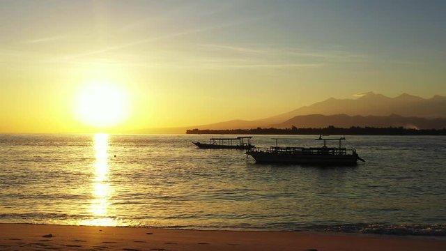 Indonesian big boats for long touring, floating over shiny quiet lagoon surface at sunset yellow sky of Philippines