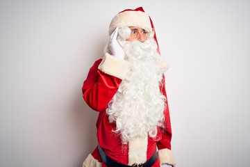Middle age handsome man wearing Santa costume standing over isolated white background smiling with hand over ear listening an hearing to rumor or gossip. Deafness concept.