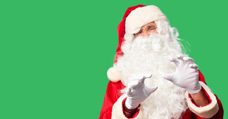 Middle age handsome man wearing Santa Claus costume and beard standing disgusted expression, displeased and fearful doing disgust face because aversion reaction. With hands raised. Annoying concept.