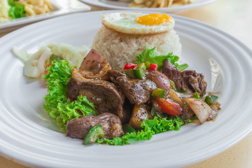 Asian Chinese Stir-fried spicy pepper beef with lettuce, jasmine white rice, pickled vegetables and sunny-side up fried egg