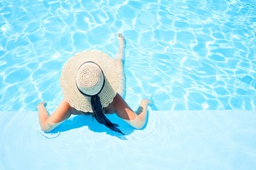 Young beautiful and sexy woman at swimming at resort pool on vacation, sunbathing inside water on sunny day